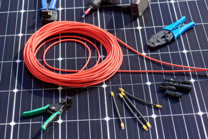 Close-up view of different details and instruments for installing and connecting solar photovoltaic system. Objects laying on blue solar panel